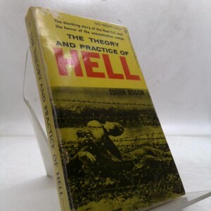May include: A vintage book titled "THE THEORY AND PRACTICE OF HELL" by Eugen Kogon. The cover is yellow with red lettering and a black and white image of a barbed wire fence and figures. The book is propped up on a clear plastic stand.