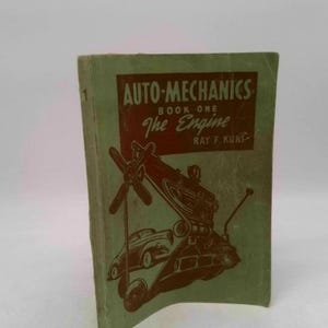 May include: Vintage "Auto-Mechanics Book One: The Engine" by Ray F. Kuns. The book has a green cover with a red and brown illustration of an engine and car. The title is in white and red text.