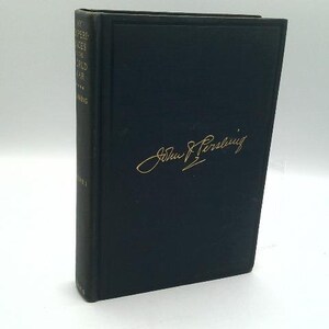 May include: A hardcover book with a dark blue cover and gold lettering. The title and author's signature are visible. The book is standing upright against a white background.