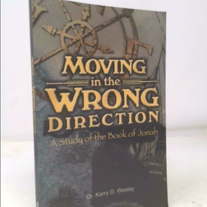 May include: Book cover with a gold compass design and the title "Moving in the Wrong Direction: A Study of the Book of Jonah" by Dr. Karry D. Wesley.