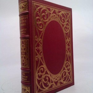 May include: A red hardcover book with gold lettering on the spine. The title is "Journey in the Dark" by Martin Levin. The book is part of The Franklin Library.
