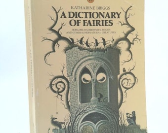 May include: A vintage book titled "A Dictionary of Fairies" by Katharine Briggs. The cover features a detailed illustration of a castle-like structure with intricate tree-like designs and the text "A Dictionary of Fairies". The book has a cream-colored background.