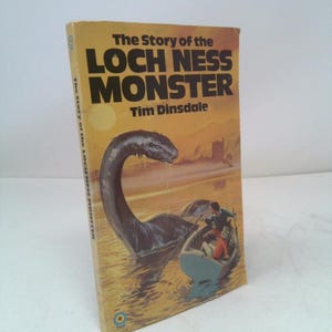 May include: A vintage book titled "The Story of the Loch Ness Monster" by Tim Dinsdale. The cover features an illustration of the Loch Ness Monster in water with a boat. The book has a yellow cover with black and white text.