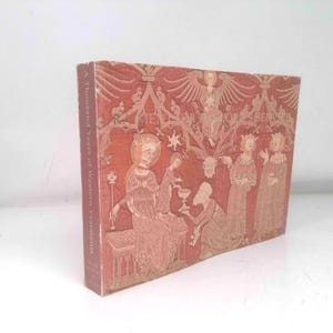 May include: A hardcover book titled "A Thousand Years of Western Vestments" with a red cover featuring an illustration of religious figures. The book is standing upright against a white background.