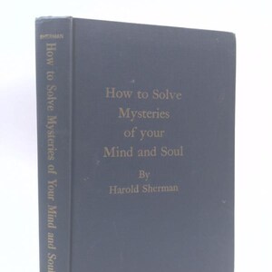 May include: A dark gray hardcover book titled How to Solve Mysteries of your Mind and Soul by Harold Sherman. The front cover and spine feature gold lettering. The spine also displays the author name Sherman and the publisher name Devorss.
