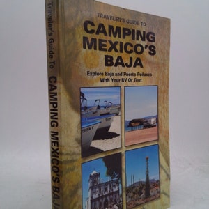 May include: A book cover with a yellow background and the title "Traveler's Guide to Camping Mexico's Baja". The cover features four photos of Baja California, including a boat on a beach, a pier, a church, and a tall cactus.