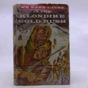 May include: A vintage book titled "We Were There in the Klondike Gold Rush." The cover features an illustration of two people in winter clothing, a dog, and a snowy mountain backdrop. The book's cover is worn.