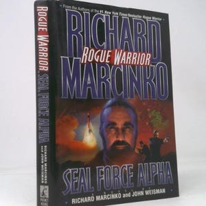 May include: A hardcover book titled "Rogue Warrior" by Richard Marcinko. The cover features a portrait of a man and the text "Seal Force Alpha". The background shows a rocket launch and silhouettes.