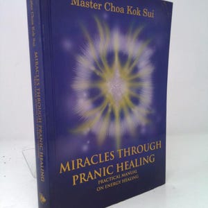 May include: A hardcover book titled "Miracles Through Pranic Healing" by Master Choa Kok Sui. The cover is dark blue with gold lettering and a central illustration of a yellow and white burst of light. The spine also features the title.