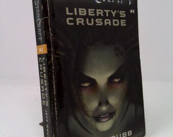 May include: A paperback book titled "StarCraft: Liberty's Crusade #1" by Jeff Grubb. The cover features a dark image of a woman's face with glowing yellow eyes. The book is based on the #1 computer game.