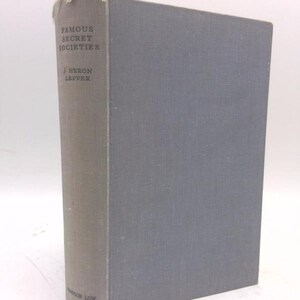 May include: A hardcover book titled "Famous Secret Societies" by J. Heron Lepper. The book has a gray cover and spine with the title and author's name printed in black. The book's spine is a lighter shade of gray than the cover.