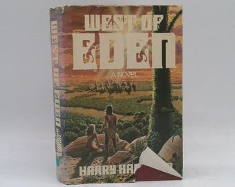 May include: A vintage paperback book titled "West of Eden: A Novel" by Harry Harrison. The cover art features a landscape with figures and creatures, with a sunset backdrop. The book has a worn appearance.