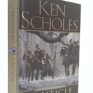May include: A hardcover book titled "Canticle" by Ken Scholes. The cover features a wintery scene with figures on horseback and the title in gold lettering. The spine reads "Ken Scholes" and "Canticle".