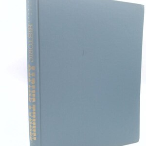 May include: A hardcover book with a solid slate blue cover. The spine features gold-colored lettering that reads "HISTORIC ALPINE TUNNEL" vertically. The book is positioned upright, showing the front cover and the spine clearly against a plain background.