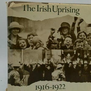 May include: A book cover titled "The Irish Uprising" with a sepia-toned photograph of people. The image includes a group of smiling people and a crowd of people with their arms raised. The years 1916-1922 are printed at the bottom.