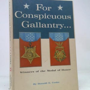 May include: A hardcover book titled For Conspicuous Gallantry... Winners of the Medal of Honor by Donald E. Cooke. The cover features a dark blue top section with white stars and two illustrations of military medals on a red background.