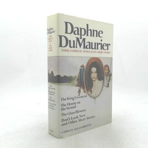 May include: A hardcover book titled "Daphne DuMaurier: Three Complete Novels & Five Short Stories." The cover features a portrait of a woman in an oval frame, with text listing the included stories. The book is in good condition.