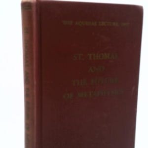 May include: A maroon hardcover book titled St. Thomas and the Future of Metaphysics, The Aquinas Lecture 1957. The front cover features gold embossed text, and the spine displays the title in gold lettering against the dark red fabric cover.