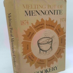 May include: A vintage cookbook titled "Melting Pot of Mennonite Cookery." The cover is beige with brown text and illustrations. The title is in large letters, with the years 1874 and 1974. A central graphic depicts a pot with steam.