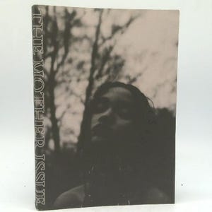 May include: A book titled "THE MOTHER ISSUE" with a sepia-toned image of a person and trees. The title is printed vertically on the left side of the book. The image on the cover is a portrait of a person with a blurred background of trees.