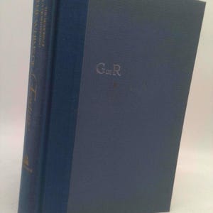 May include: A hardcover book with a dark blue spine and cover. The spine features gold lettering and the title "The Antinomies of Culture". The cover has the initials "G de R" embossed in a lighter shade of blue.