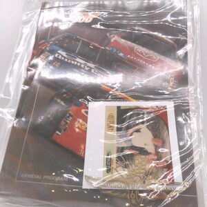 May include: A close-up of a program for the Brickyard 400 race at the Indianapolis Motor Speedway. The program features a photo of a race car and a smaller photo of a driver. The program is in a clear plastic bag.