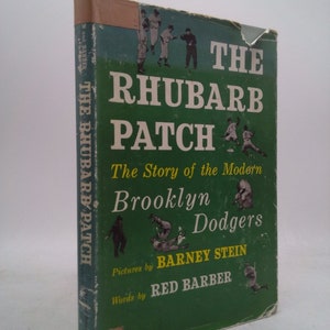 May include: A green book titled "The Rhubarb Patch: The Story of the Modern Brooklyn Dodgers" with illustrations of baseball players. The book is by Barney Stein and Red Barber.