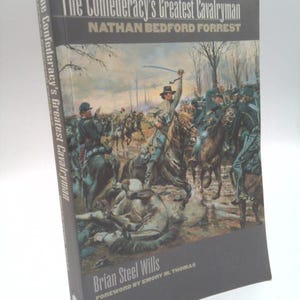 May include: A hardcover book titled "The Confederacy's Greatest Cavalryman" by Brian Steel Wills. The cover features a painting of cavalry soldiers in battle. The author's name and the title are in white text on a dark gray background.
