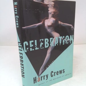 May include: A hardcover book titled "Celebration" by Harry Crews. The cover features a woman underwater with arms outstretched, set against a black background with a turquoise triangle. The book's spine also displays the title.