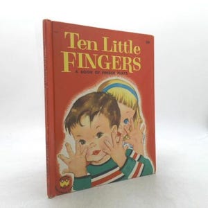 May include: A vintage children's book titled "Ten Little Fingers" with a red cover. The cover features illustrations of two children, one with brown hair and the other with blonde hair. The book is a book of finger plays.