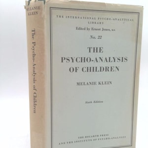 May include: A vintage book titled "The Psycho-Analysis of Children" by Melanie Klein. The book has a light-colored cover with black text and a framed border. The spine displays the title and author. The book is a sixth edition from The Hogarth Press.