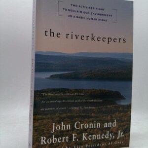 May include: A hardcover book titled The Riverkeepers by John Cronin and Robert F. Kennedy, Jr. The cover features a landscape photograph of a river winding through a forest at dusk. Text includes Two activists fight to reclaim our environment.