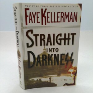 May include: A hardcover book titled "Straight Into Darkness" by Faye Kellerman. The cover features the title in large, black letters, with the author's name in red. The background shows a dark, sepia-toned image of a building and figures.
