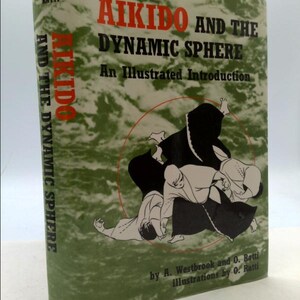 May include: A book cover with a green background and a black and white illustration of three people practicing Aikido. The title of the book is "Aikido and the Dynamic Sphere: An Illustrated Introduction" by A. Westbrook and O. Ratti.