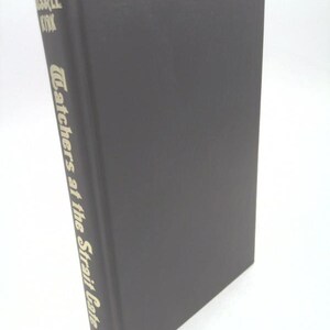 May include: A dark gray hardcover book with the title "Catchers at the Strait Gate" in gold lettering on the spine.