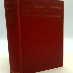 May include: A red hardcover book titled "The Caliph of Bagdad" by O. Henry, with the names Robert H. Davis and Arthur B. Maurice printed below. The book has gold lettering and the word "APPLETON" printed on the bottom spine.
