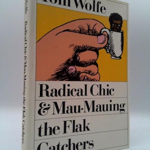 May include: A hardcover book titled Radical Chic & Mau-Mauing the Flak Catchers by Tom Wolfe. The cover features a yellow background with a black and white illustration of a large hand holding a small white teacup containing a person's head.