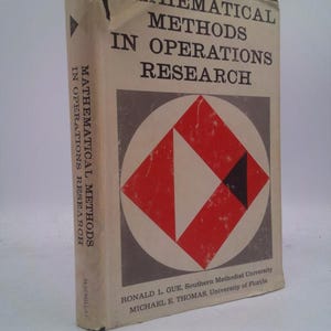 May include: A vintage book titled "Mathematical Methods in Operations Research." The cover features a geometric design with red, white, and black shapes within a gray circle. The book's spine also displays the title. The book is slightly worn.