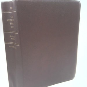 May include: A brown leather-bound Bible with gold lettering on the spine. The text on the spine reads "Life Application Study Bible" and "King James Version". The book is a large format.
