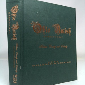 May include: A dark green book titled "Ohio Amish Directory" with gold lettering. The cover reads "Holmes County and Vicinity" and "2000 Millennium Edition". The book's spine also features the title and edition details.