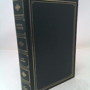 May include: A hardcover book titled "Divine Comedy" by Dante Alighieri. The book has a black cover with gold trim and gold lettering on the spine. The spine also features decorative gold accents. The book is part of "The Illustrated Classics" series.