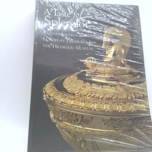 May include: A book titled "A Taste for Splendor" featuring Russian Imperial and European treasures from The Hillwood Museum. The cover displays a gold-colored, ornate vessel with intricate details and a dark background.