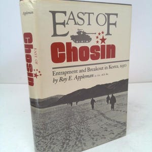 May include: A hardcover book titled "East of Chosin" by Roy E. Appleman. The cover features the title in large, bold letters with a tank illustration and silhouettes of people walking in a snowy landscape. The spine also displays the title.