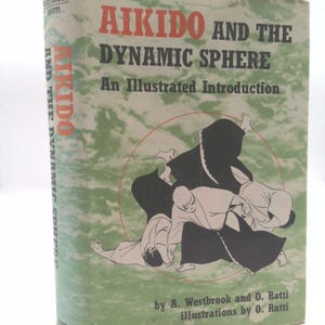 May include: Book cover with a green background and a black and white illustration of two people practicing Aikido. The title of the book is "Aikido and the Dynamic Sphere: An Illustrated Introduction" by A. Westbrook and O. Ratti.