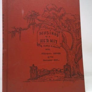 May include: A vintage book with a red cover featuring the title "Musings of a Hermit" in a decorative font. The cover includes a detailed illustration of a tree and a landscape scene, all in black ink.