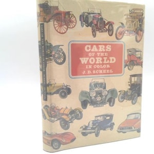 May include: A vintage book titled "Cars of the World in Color" by J.D. Soheel. The cover features illustrations of classic cars in various colors, set against a beige background. The book's title is in a red rectangular box.