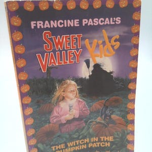 May include: A paperback book titled "Sweet Valley Kids" by Francine Pascal. The cover features a young girl in a pink dress holding a flashlight in a pumpkin patch with a witch and black cat. The book has a purple border with orange pumpkins.
