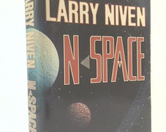 May include: A vintage paperback book titled "N-SPACE" by Larry Niven. The cover features a dark blue background with a planetary scene and the title in large, red letters. The book includes an introduction by Tom Clancy.