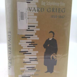 May include: A hardcover book titled "Edvard Grieg" by Dag Schjelderup-Ebbe. The cover is tan with a piano key design and a silhouette of a person. The book's title and author's name are printed in black. The publisher's name is also visible.