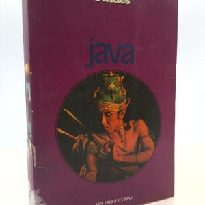May include: A vintage travel guide titled "Java" with a maroon cover. The cover features the text "Insight Guides" and "Java" in white. A circular image depicts a person in traditional Indonesian attire. "APA PRODUCTIONS" is printed at the bottom.